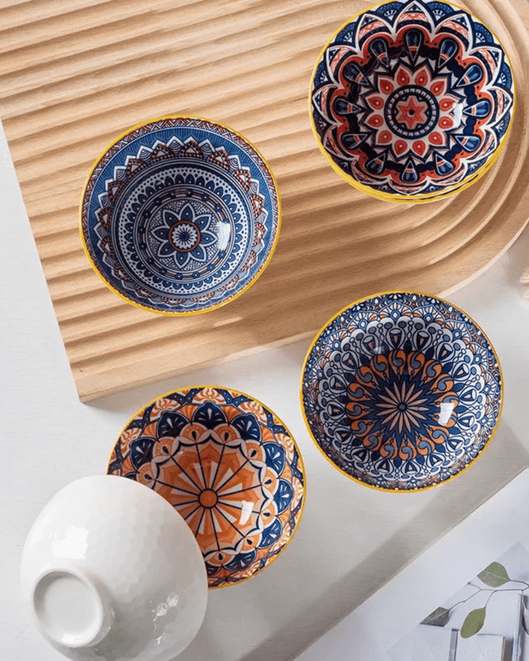 Hand-painted ceramic bowl set in vibrant Bohemian designs on a wooden surface, perfect for dining.