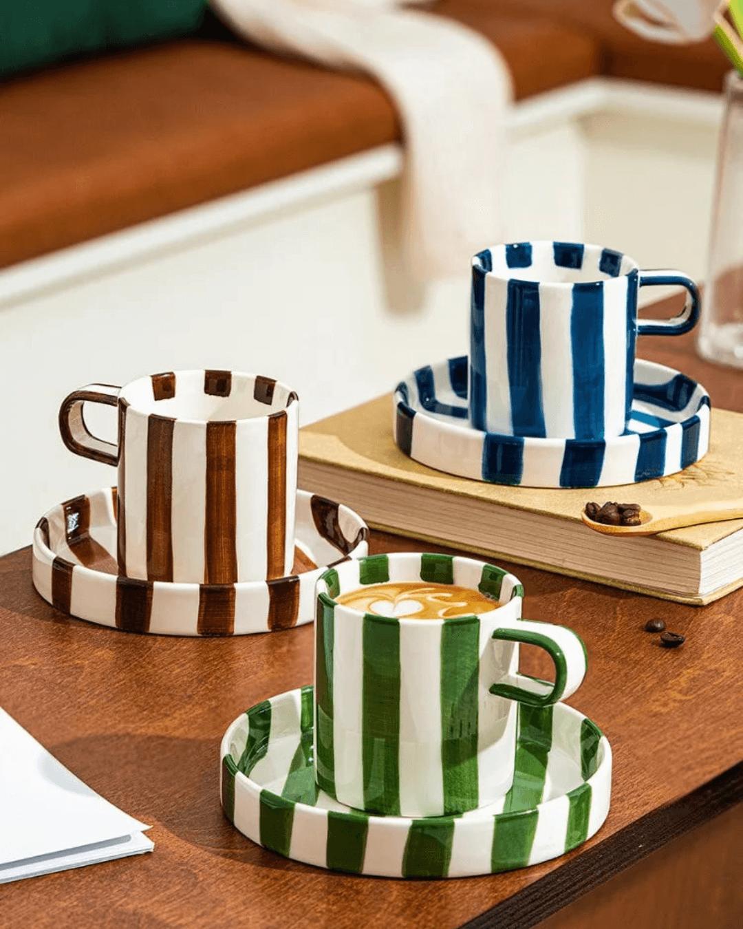 Ceramic coffee mug set with retro striped design and matching saucers on a wooden table.