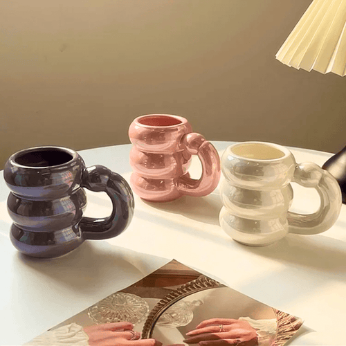 Ceramic Bubble Mugs in iridescent pastel colors with stacked-ring handles on a table, perfect for stylish coffee and tea.
