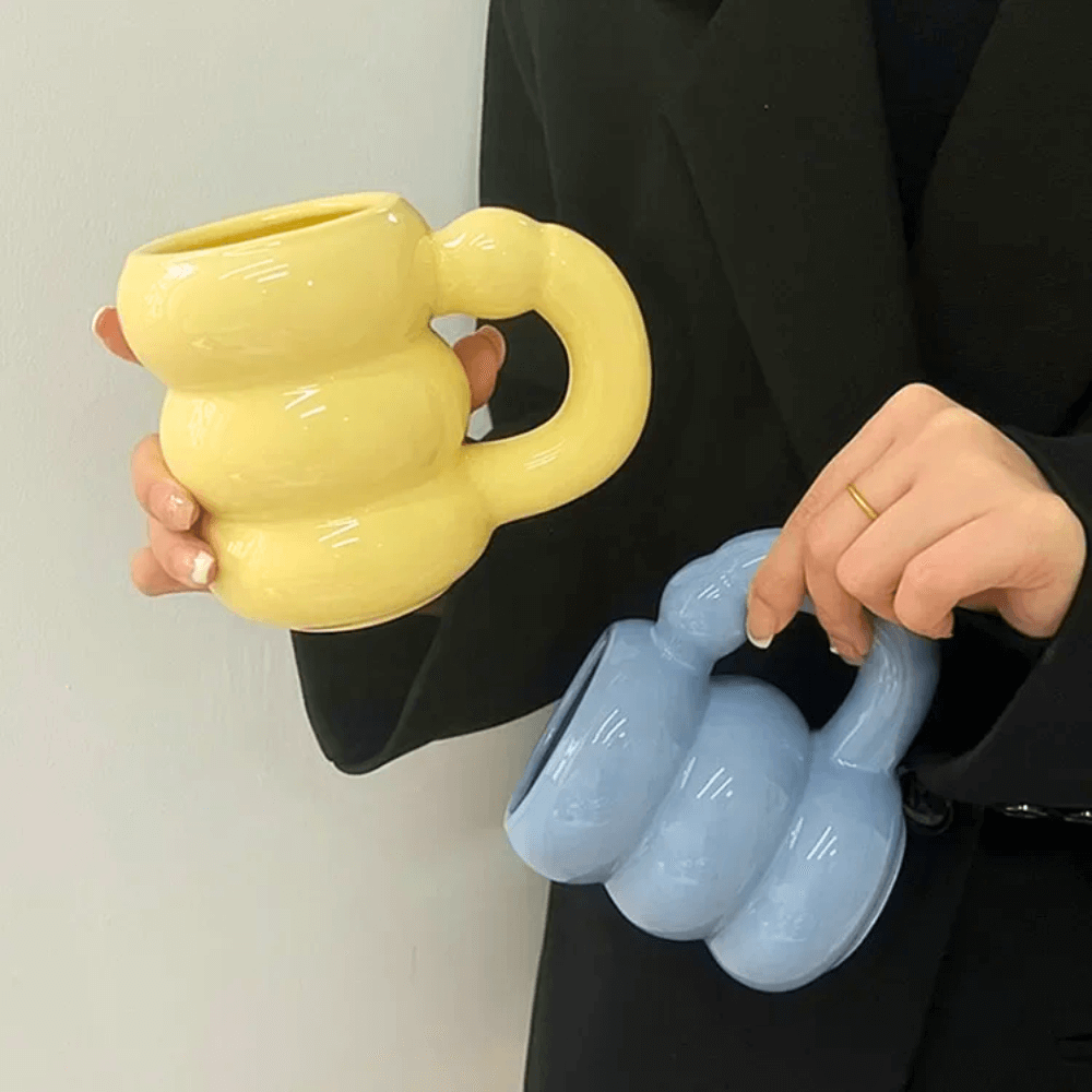 Ceramic bubble mugs in pastel yellow and blue with stacked-ring handles for a comfy grip.