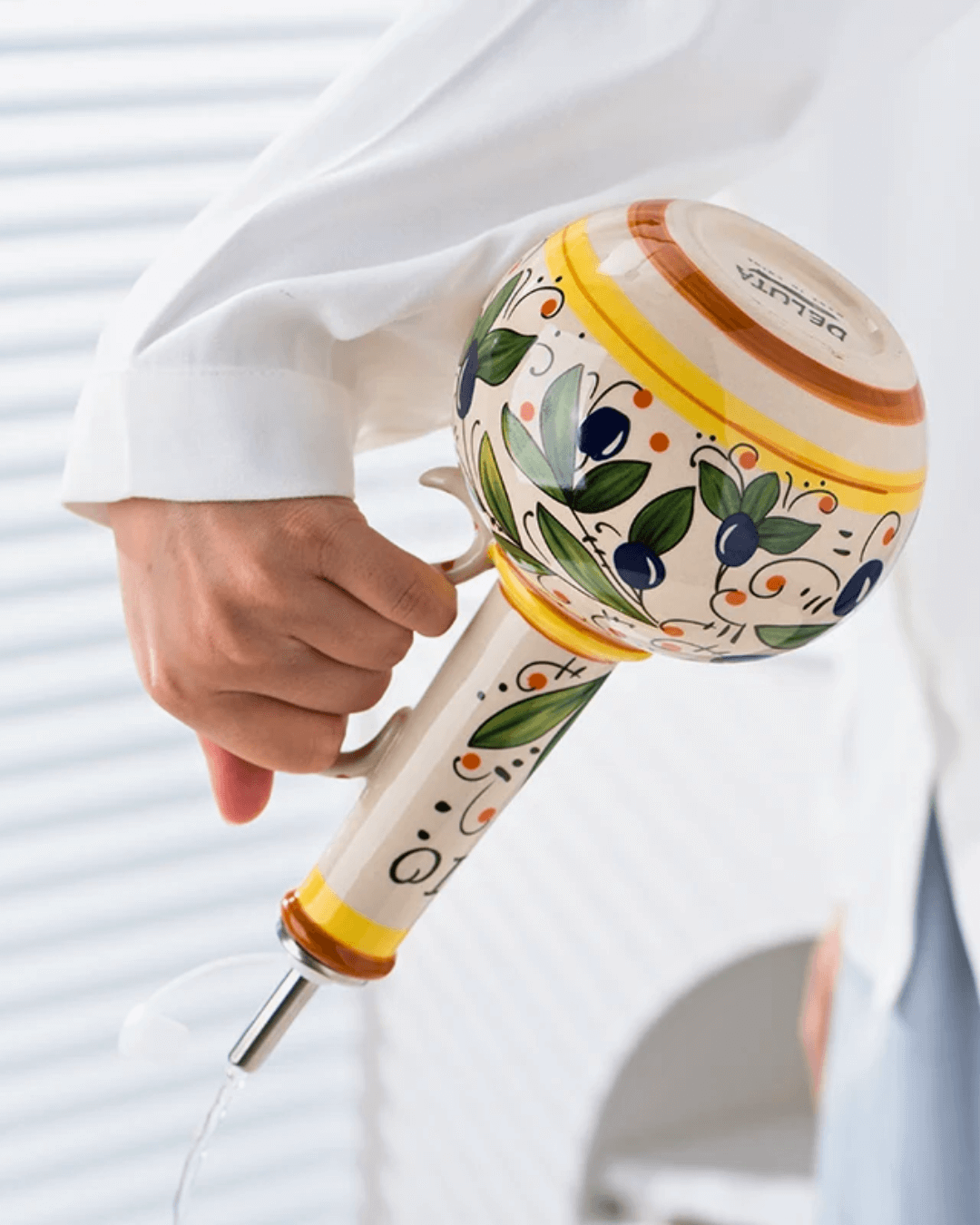 Hand-painted ceramic olive oil dispenser with leak-proof spout, showcasing Mediterranean design in use.