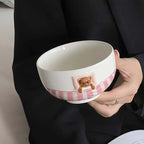 Ceramic bowl with Sweet Dream Bear design, featuring a pink striped band, held by a person.