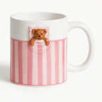 Ceramic mug with Sweet Dream Bear design, featuring a cute bear peeking from pink striped pattern.