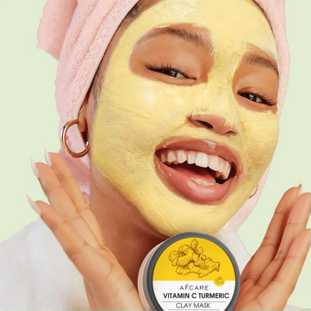 Person enjoying a Vitamin C Turmeric clay mask, showcasing a radiant smile and glowing skin.