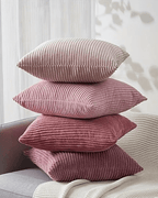 Stack of soft pink corduroy decorative pillow covers in boho style on a sofa.