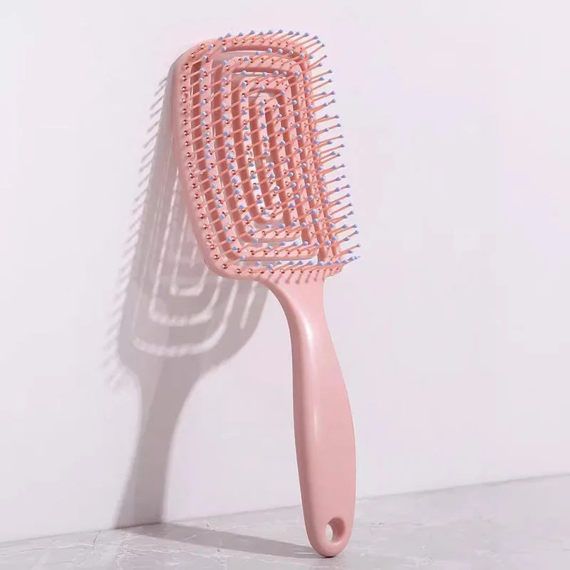 Detangling hair brush with hollow vent design in pink color, ideal for scalp massage and quick drying.