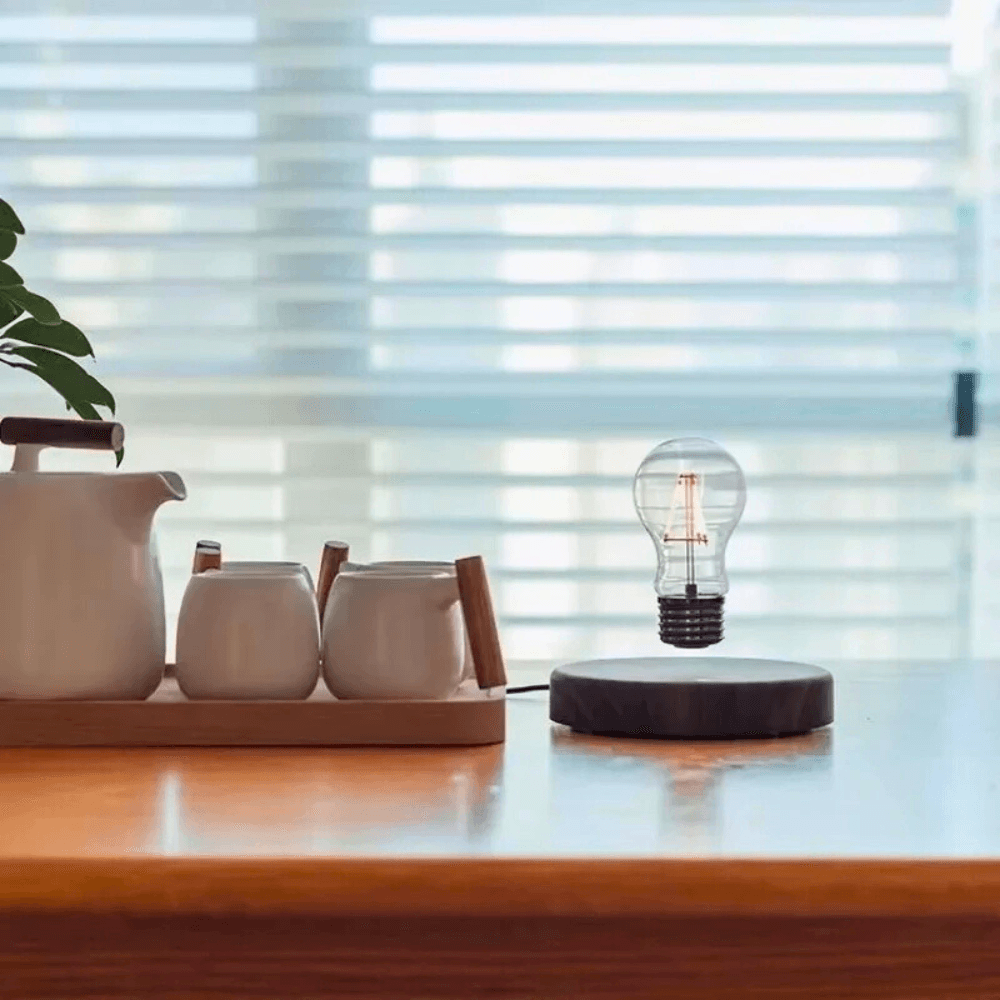 Levitating LED bulb on walnut base with coffee set, showcasing modern ambiance and design.