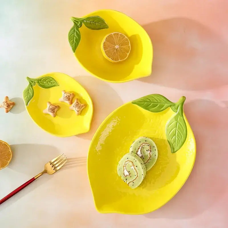Lemon-shaped ceramic tableware set with yellow plates, bowls, and snacks for vibrant dining experiences.