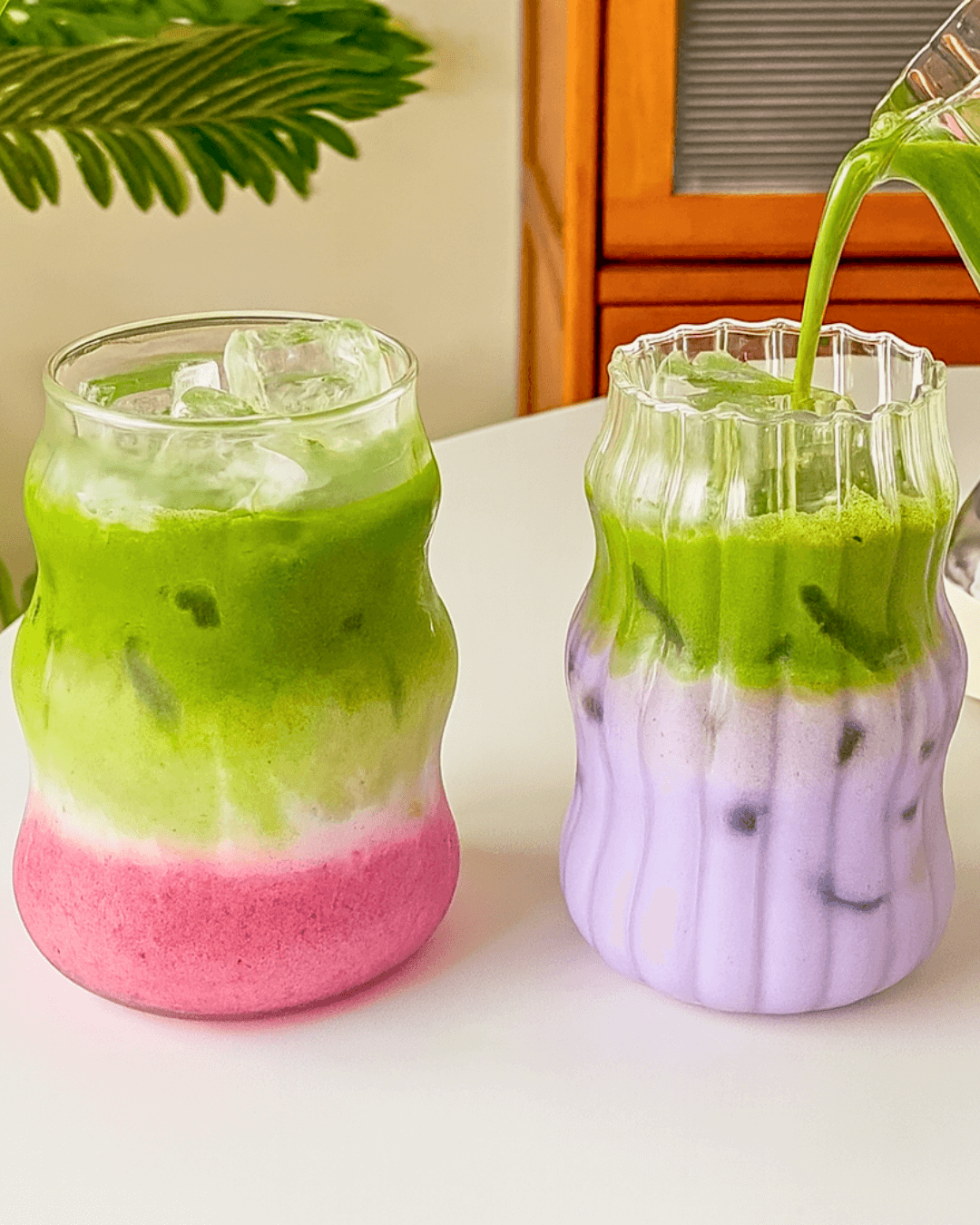 Two 500ml heat-resistant matcha glasses filled with layered iced drinks, showcasing vibrant green and purple colors.