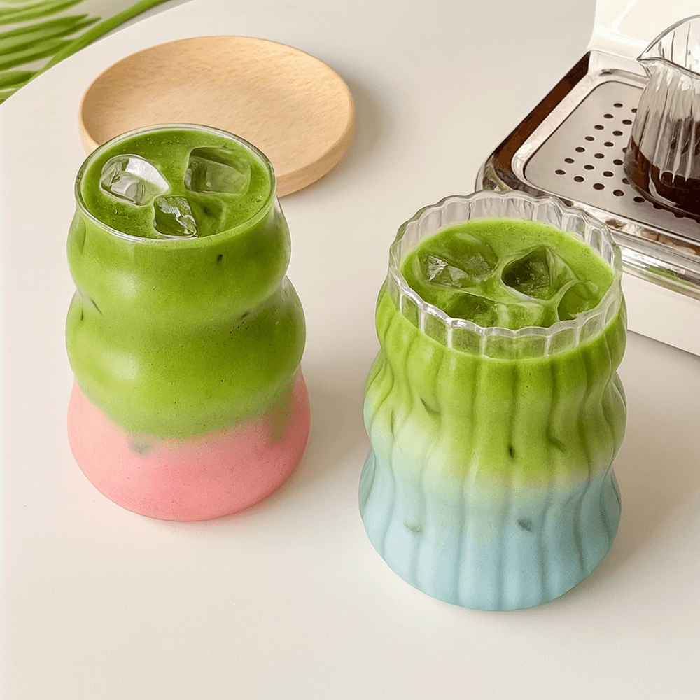 Two colorful wavy matcha glasses filled with iced matcha drinks on a stylish table.