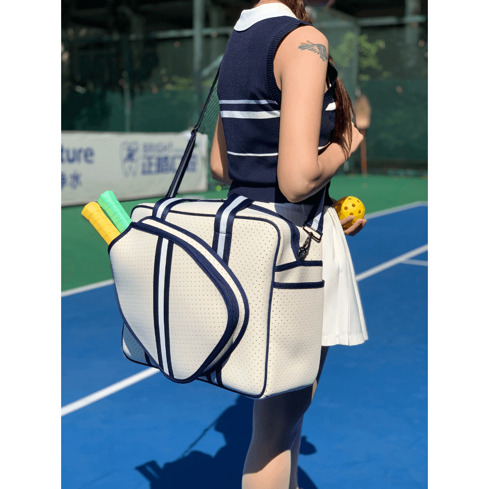 Waterproof neoprene padel racket bag with external sleeve, carried on shoulder by player on court.