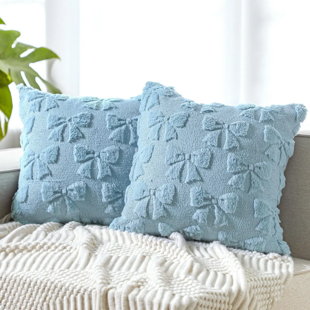 Set of 2 plush cushion covers in soft blue with quilted bow pattern, ideal for sofas or beds.