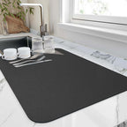 Quick-drying kitchen mat on marble countertop, featuring dishes and silverware, ideal for absorbing water and keeping surfaces dry.