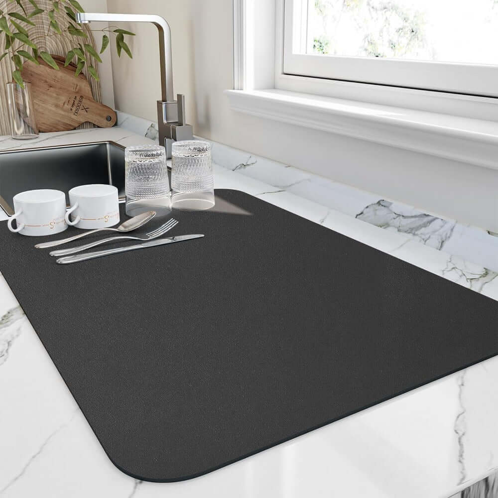 Quick-drying kitchen mat on marble countertop, featuring dishes and silverware, ideal for absorbing water and keeping surfaces dry.