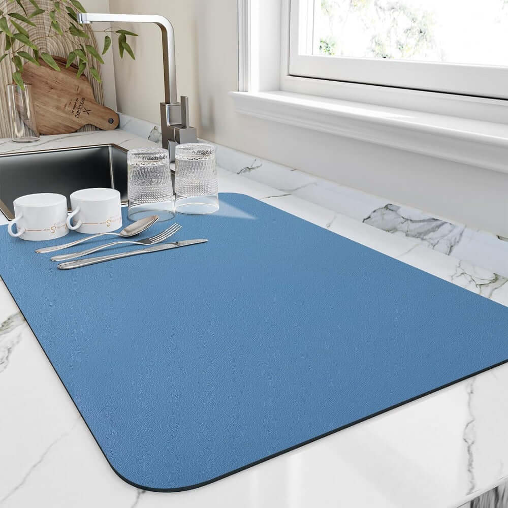 Blue quick-drying kitchen mat placed next to a sink with dishes and utensils, ideal for absorbing water.