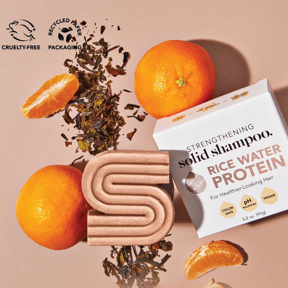 Solid rice water shampoo bar with oranges and tea leaves, promoting healthier hair, cruelty-free and eco-friendly packaging.