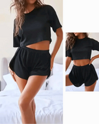 Women's black pajama set featuring a cropped t-shirt and loose shorts, designed for comfort and style.