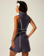 Back view of a woman in a stylish padel tennis dress with zip polo neck and flared skirt, showcasing ball pockets.