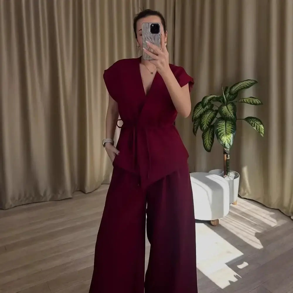 Women’s two-piece set featuring sleeveless belted V-neck top and wide-leg trousers in deep burgundy, perfect for summer outings.