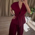 Women’s two-piece set featuring a sleeveless belted V-neck top and wide-leg trousers in burgundy.