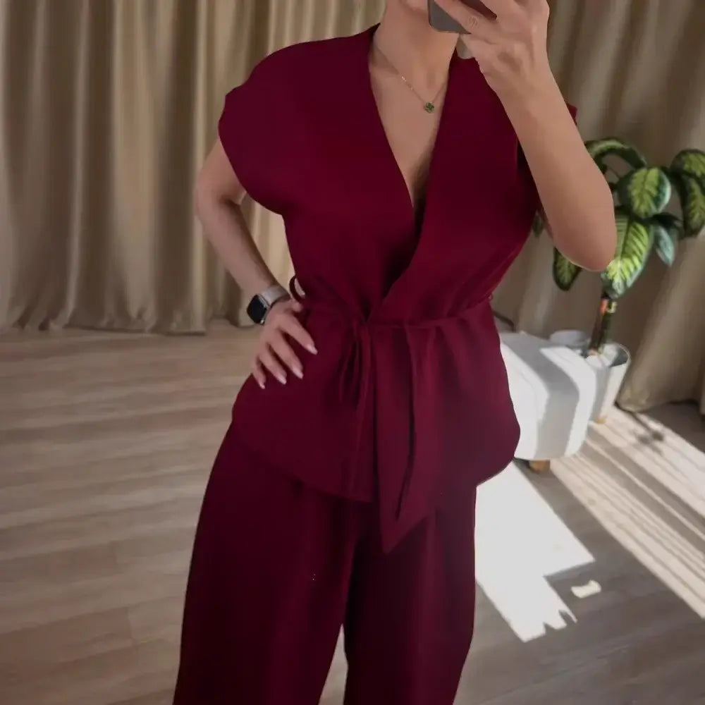 Women’s two-piece set featuring a sleeveless belted V-neck top and wide-leg trousers in burgundy.