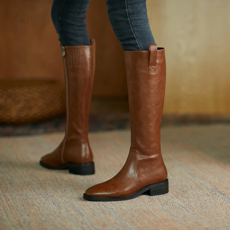 Brown knee-high leather boots with a chunky heel, elegantly styled for women, perfect for any outfit.