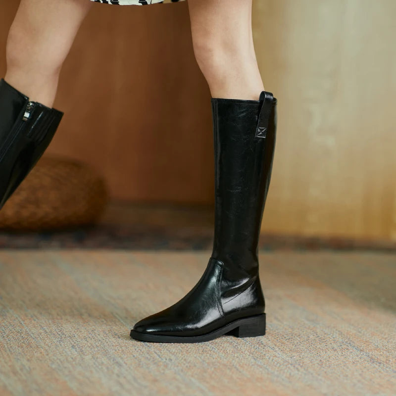 Women’s knee-high black leather boots with a pointed toe and chunky heel, showcasing elegance and durability.