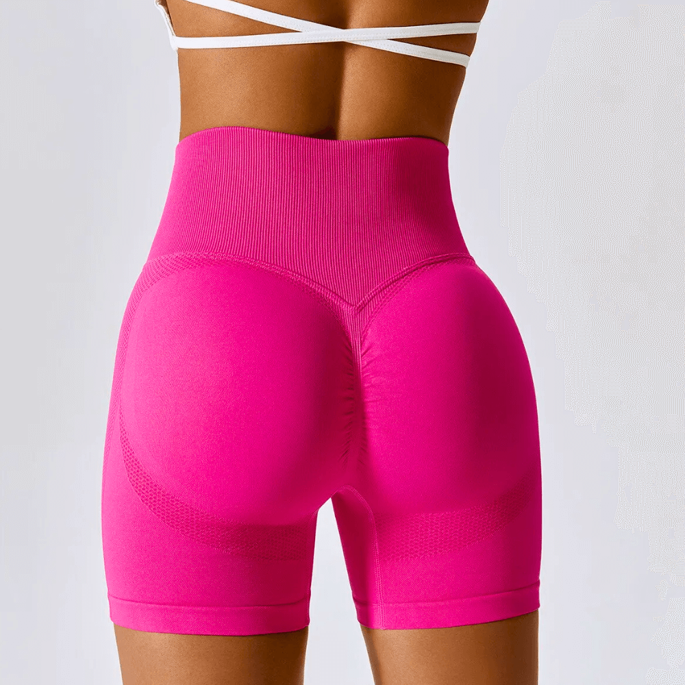 Womens high-waisted seamless workout shorts in vibrant pink, featuring a ribbed waistband and supportive fit for gym and yoga.