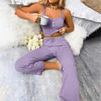 Relaxed woman in soft ribbed lace pajama set, enjoying a cup of tea in a cozy bedroom setting.