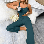 Woman in ribbed lace pajama set with camisole and drawstring pants, holding a cup in a cozy indoor setting.