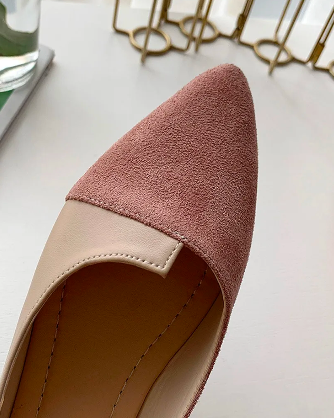 Close-up view of pointed toe ballet flats in soft pink faux suede, featuring a chic and elegant design.