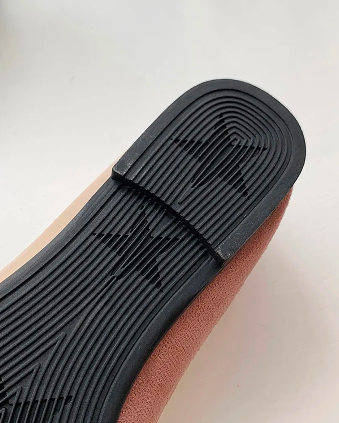 Close-up of the rubber sole of black pointed toe flats featuring star patterns for added grip and style.