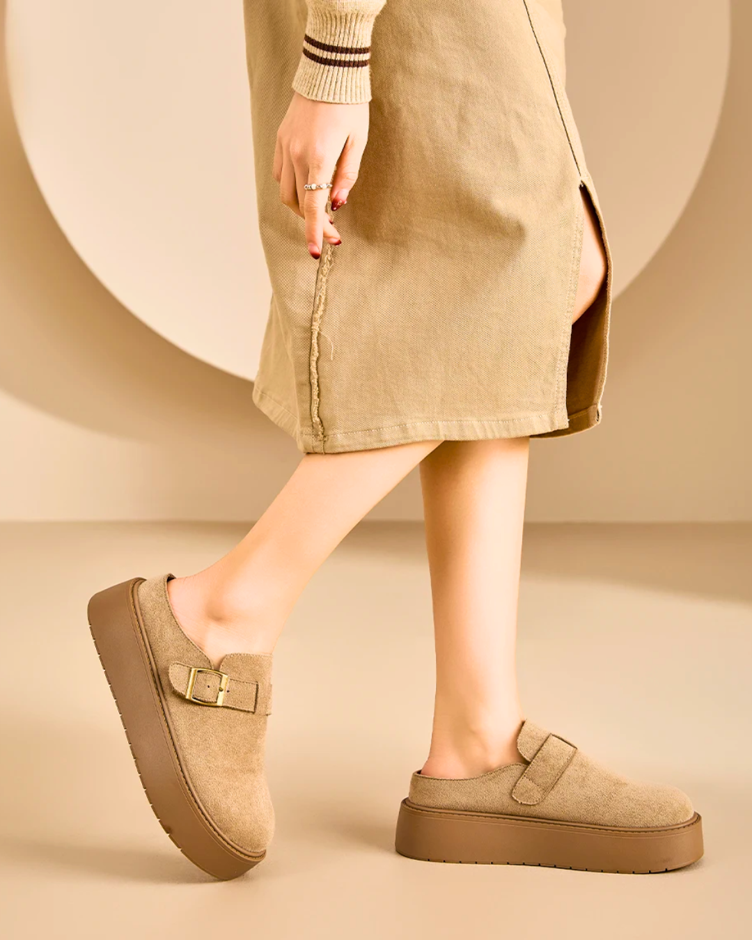Woman wearing beige suede platform clog mules with buckle, showcasing stylish comfort in a casual outfit.