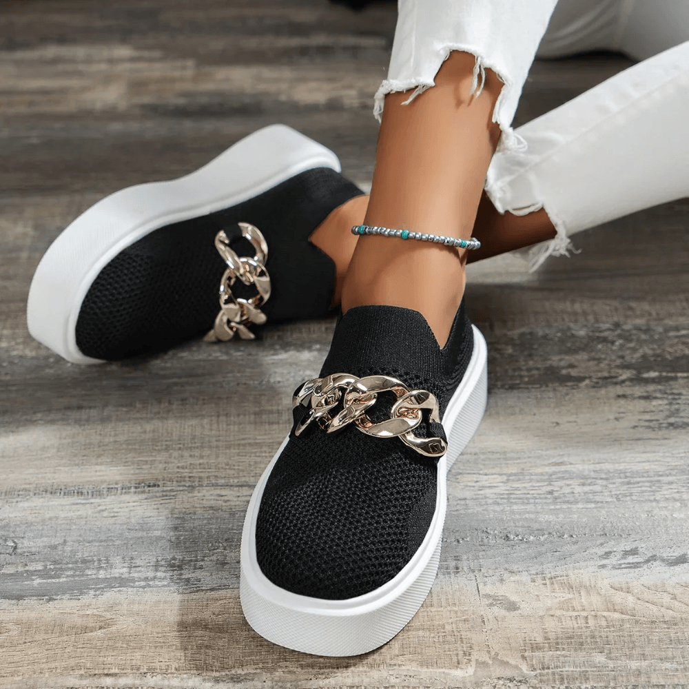Stylish black slip-on shoes with chain detailing, perfect for casual wear and comfort.