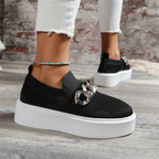 Stylish black women's slip-on shoes with chain detail and white platform sole, perfect for casual outings.