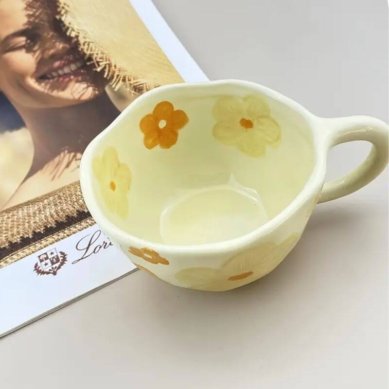 Flower-pattern ceramic mug with a unique hand-drawn design in yellow and orange, perfect for coffee or tea.