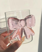 Pink bow glass cup held in hand with light reflection - aesthetic handmade drinking glass
