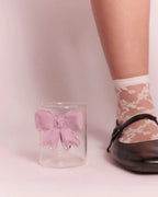 Pink bow glass cup next to model’s shoe - size comparison image for aesthetic drink ware