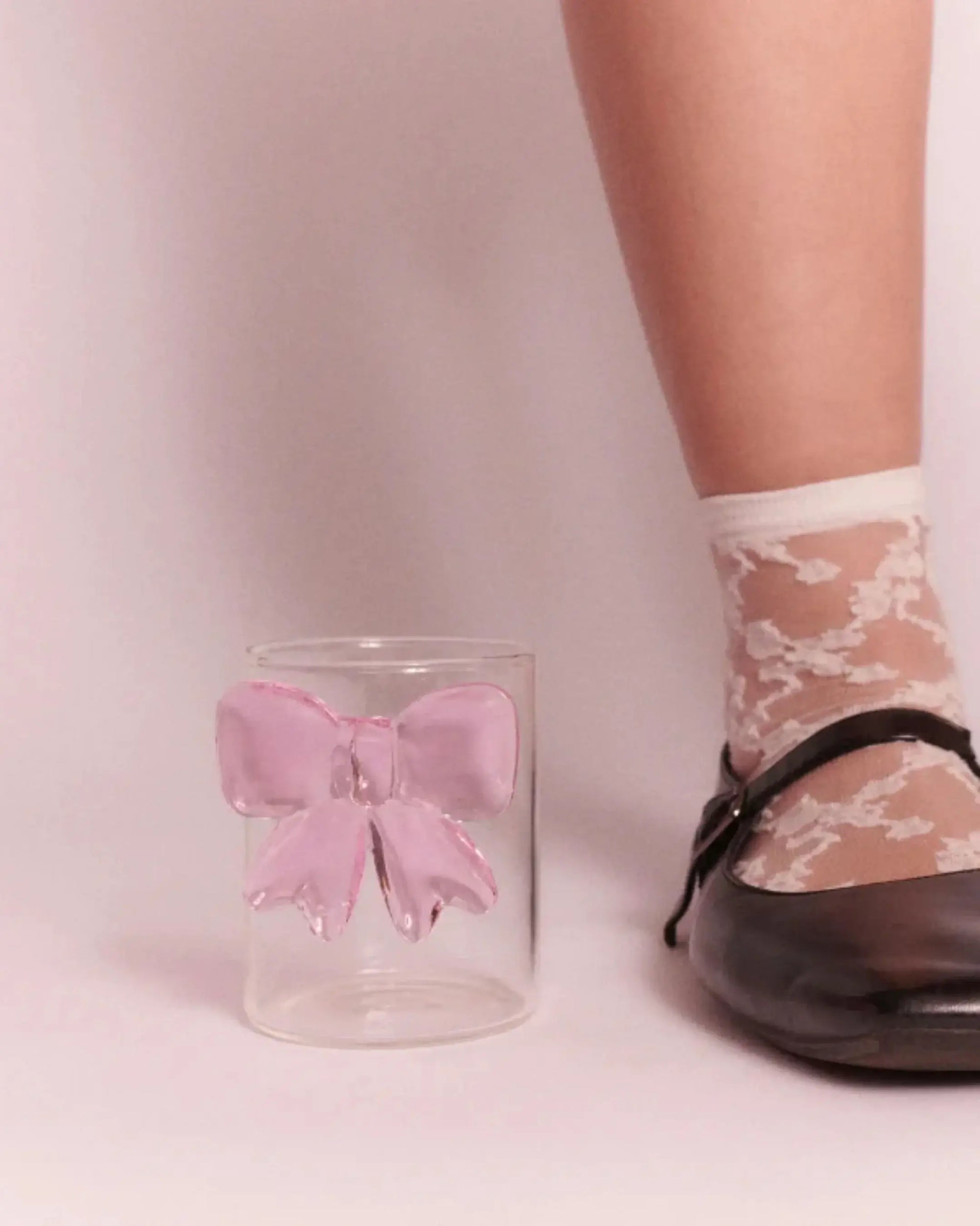 Pink bow glass cup next to model’s shoe - size comparison image for aesthetic drink ware