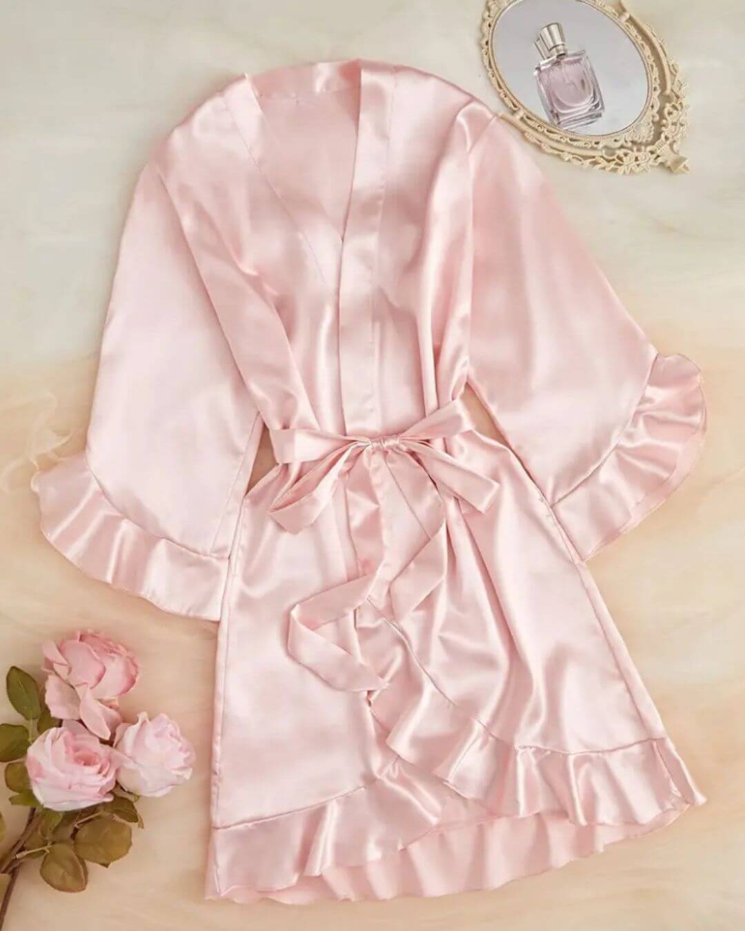 Women's pink satin short dressing gown with ruffle sleeves and tie belt, perfect for luxurious lounging.