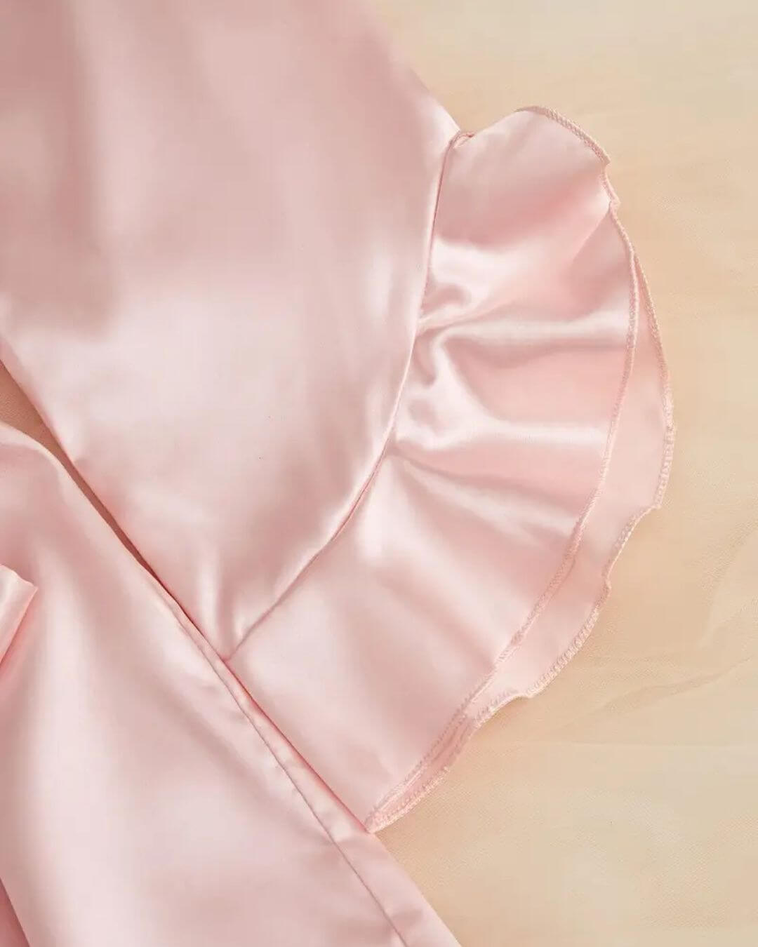 Close-up of soft pink satin with ruffled hem, showcasing the luxurious fabric of a women's dressing gown.